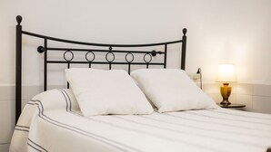 Ein Bett mit Metallgestell, weißer Bettwäsche und einer Nachttischlampe.