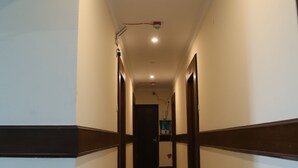 Um corredor longo e estreito com piso lustroso, paredes brancas e detalhes escuros.