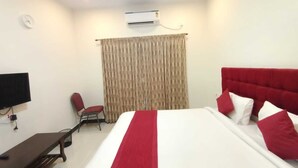 Quarto de hotel com cama grande, TV de tela plana, escrivaninha e cadeira.