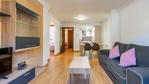 A modern living room with a TV, sofa, and dining area.