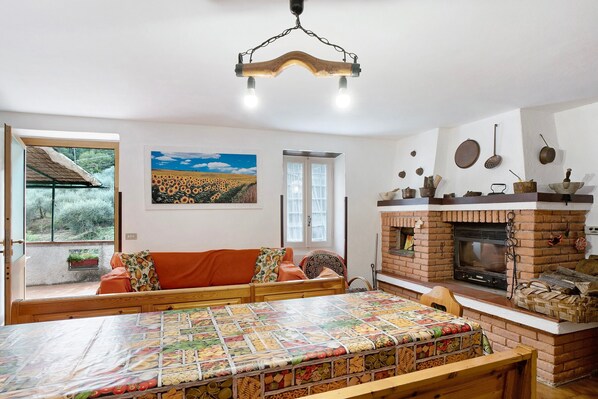A cozy room with a wooden bench, a quilted table, a fireplace, and a view of the outdoors.