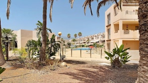 Un immeuble résidentiel doté de balcons, d’une piscine et de palmiers.