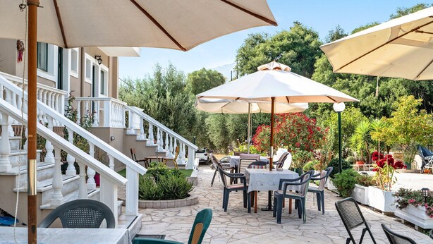 A patio area with outdoor seating, umbrellas, and a staircase leading to a building. - Studio "Daratos 4" with Shared Garden & Wi-Fi (KEFALONIA)