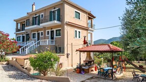 A multi-story building with balconies, a patio area with outdoor furniture, and a playground. - Studio "Daratos 4" with Shared Garden & Wi-Fi (KEFALONIA)