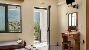 A bedroom with a bed, a desk, a chair, and a window with a view of greenery. - Studio "Daratos 4" with Shared Garden & Wi-Fi (KEFALONIA)