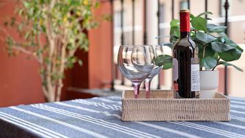 Une bouteille de vin et un verre sur une table recouverte d’une nappe à rayures, un plateau en osier et une plante en pot en arrière-plan.