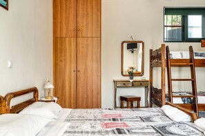 Un dormitorio con un armario de madera, una mesita de noche con lámpara, un espejo, un escritorio con silla y una cama litera.