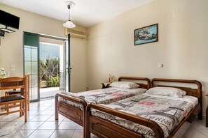 Un dormitorio con cama, escritorio, silla, televisor y balcón con vistas.
