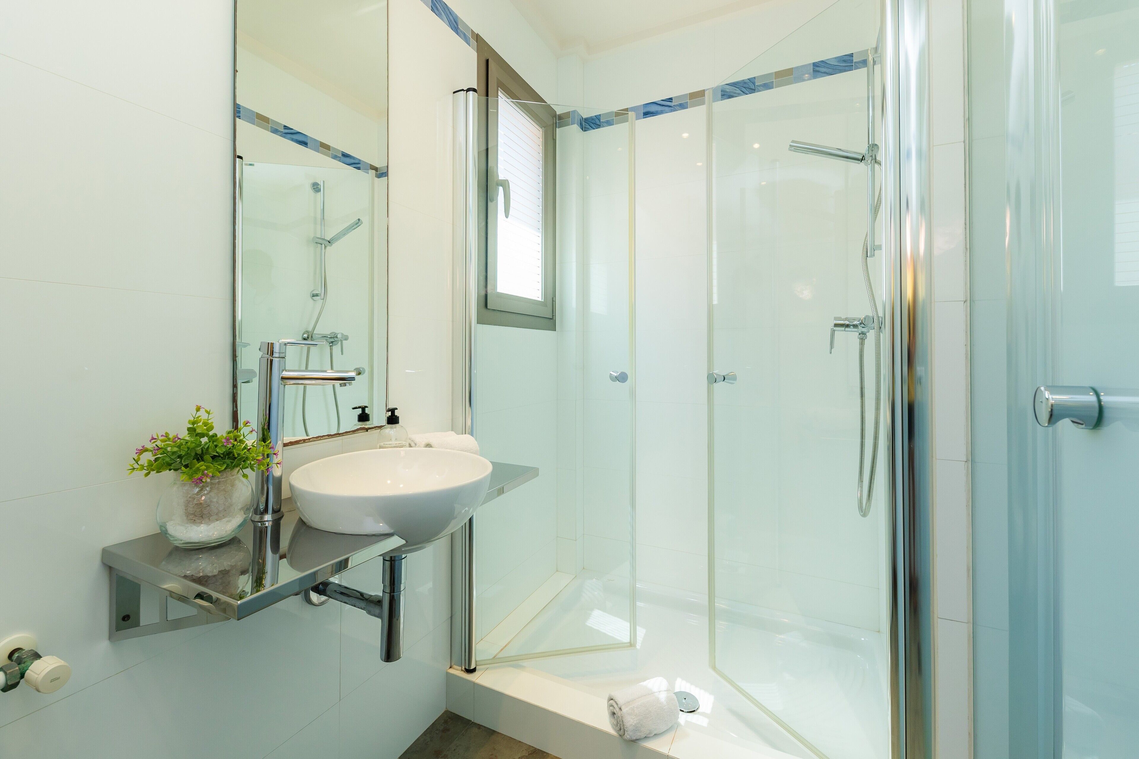Un bagno moderno con doccia vetrata, lavandino bianco e specchio sopra il lavandino.
