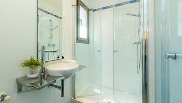Un bagno moderno con doccia vetrata, lavandino bianco e specchio sopra il lavandino.