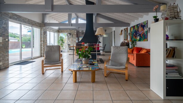 Een ruime woonkamer met een hoge plafond, grote ramen en een moderne open haard.