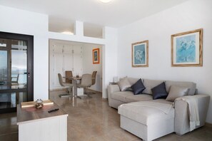 Ein modernes Wohnzimmer mit Sofa, Couchtisch und Essbereich mit Stühlen.