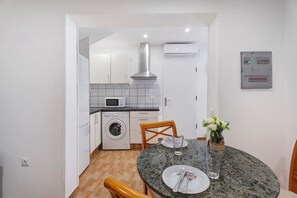 Une cuisine compacte équipée d’un lave-linge, d’un four à micro-ondes et d’un coin repas avec une table pour deux personnes.