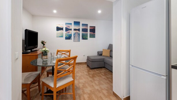 A modern living space with a dining area, a sofa, and a refrigerator.