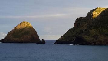A coastal landscape with two prominent rock formations and calm sea.