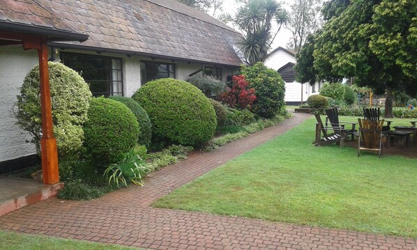 A building with a brick pathway leading to a seating area with wooden furniture.
