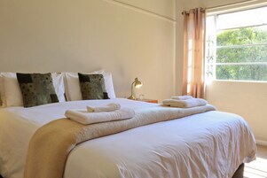 Una cama bien hecha con toallas, una lámpara y una ventana con cortinas.