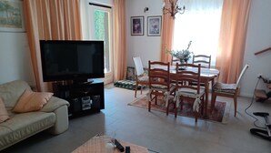 Un soggiorno con televisione, divano, tavolo da pranzo e sedie.