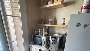 A compact kitchen with a wooden table, a microwave, a kettle, a toaster, and a refrigerator. - Appartement T4 à 5 min du Stade Vélodrome (Marseille)