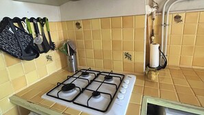 A kitchen with a gas stove, a range hood, and a tiled backsplash. - Appartement T4 à 5 min du Stade Vélodrome (Marseille)