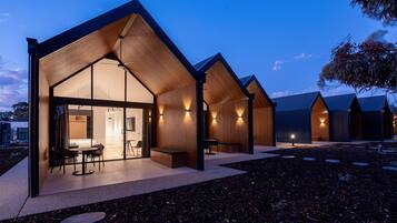 Un edificio moderno con una amplia entrada de vidrio, paredes interiores de madera y un patio con mobiliario.