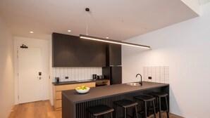A modern kitchen with a central island, bar stools, and a large window. - Par Five Shacks (Berri)