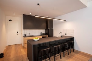 Una cocina moderna con una isla central, taburetes de bar y un ventanal grande.