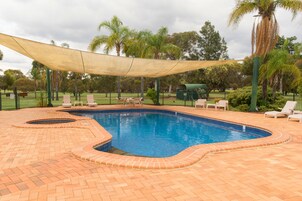 Una piscina al aire libre de temporada, sombrillas