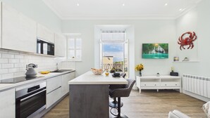 Cozinha moderna com armários brancos, uma ilha central e vista para uma varanda.