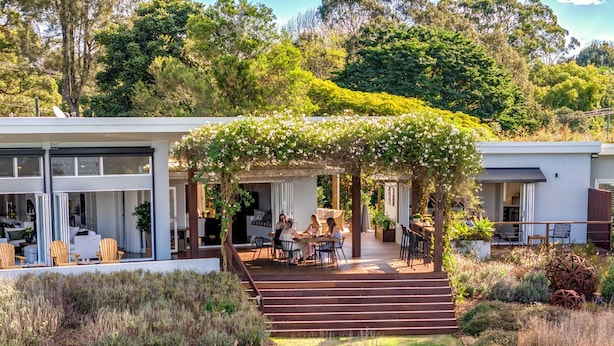 Una casa moderna con un porche cubierto, mobiliario de exterior y un jardín.