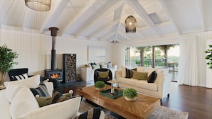 Una sala de estar amplia con chimenea, un sofá, una mesa de centro y vistas al exterior.