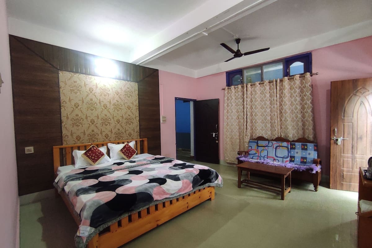 A bedroom with a bed, a wooden bench, a ceiling fan, and a door.