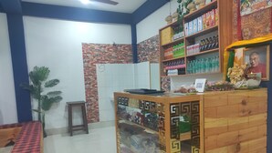 A reception area with a wooden counter, a prayer wheel, and a Buddha statue. - Eight Lucky Homestay (West Kameng)