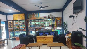 A room with a sofa, two wooden tables, and a bench with plaid cushions. - Eight Lucky Homestay (West Kameng)