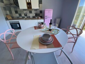 Una cocina moderna con un refrigerador rosa, una mesa de comedor con sillas rosa y vistas al exterior a través de un ventanal grande.
