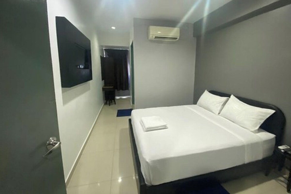 Une chambre d’hôtel moderne dotée d’un grand lit, d’un téléviseur à écran plat fixé au mur et d’un appareil de climatisation.