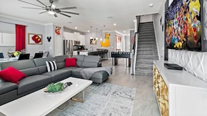A modern living room with a grey sectional sofa, a coffee table, and a large flat-screen TV. - Family-friendly escape w/ resort access & pool (Kissimmee)