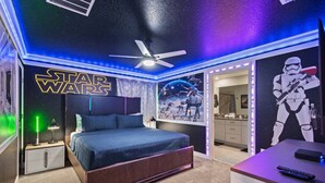 A Star Wars-themed bedroom with a bed, ceiling fan, and wall decorations including a large poster and a Stormtrooper figure. - Family-friendly escape w/ resort access & pool (Kissimmee)