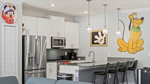 A modern kitchen with white cabinets, stainless steel appliances, and a central island with bar stools. - Family-friendly escape w/ resort access & pool (Kissimmee)