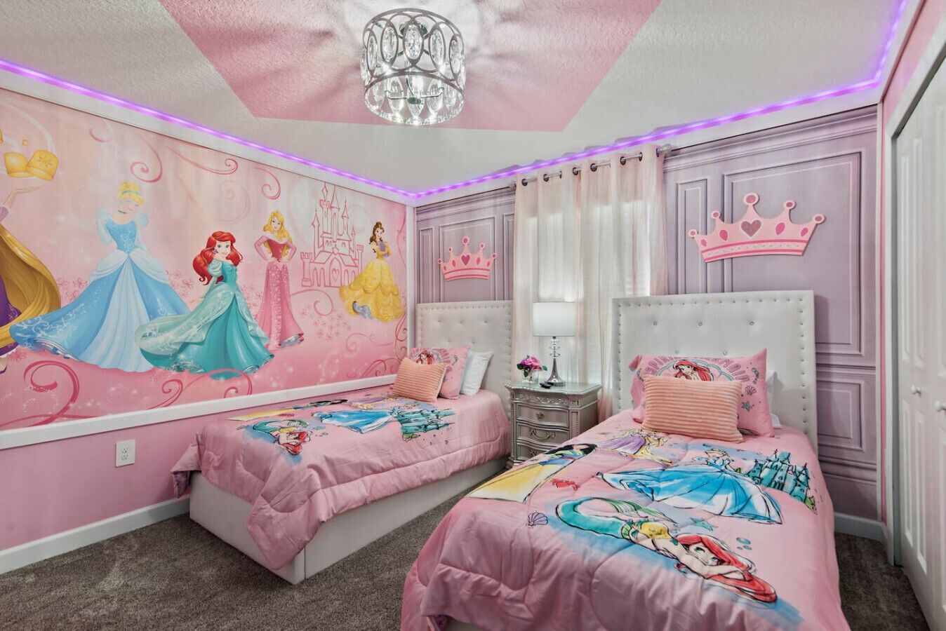 Une chambre avec deux lits, une fresque représentant les princesses Disney et un éclairage d’ambiance à diodes électroluminescentes violettes.