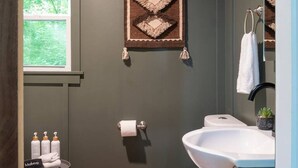 Un baño moderno con inodoro, lavabo y un adorno colgante.