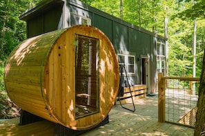 A cabin with a large wooden barrel structure, a deck, and a fenced area.