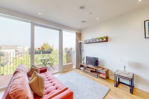 Relax in this stylish living room with a sofa, flat-screen TV, and balcony access.