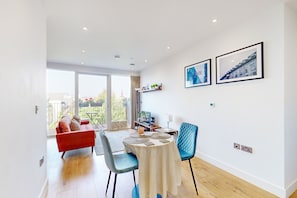 Relax in this stylish living space with a round dining table, comfortable sofa, and framed artwork.