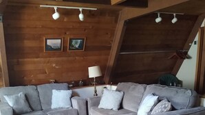 Ein gemütliches Wohnzimmer mit grauem Sofa, einem Holztisch und einer Lampe.