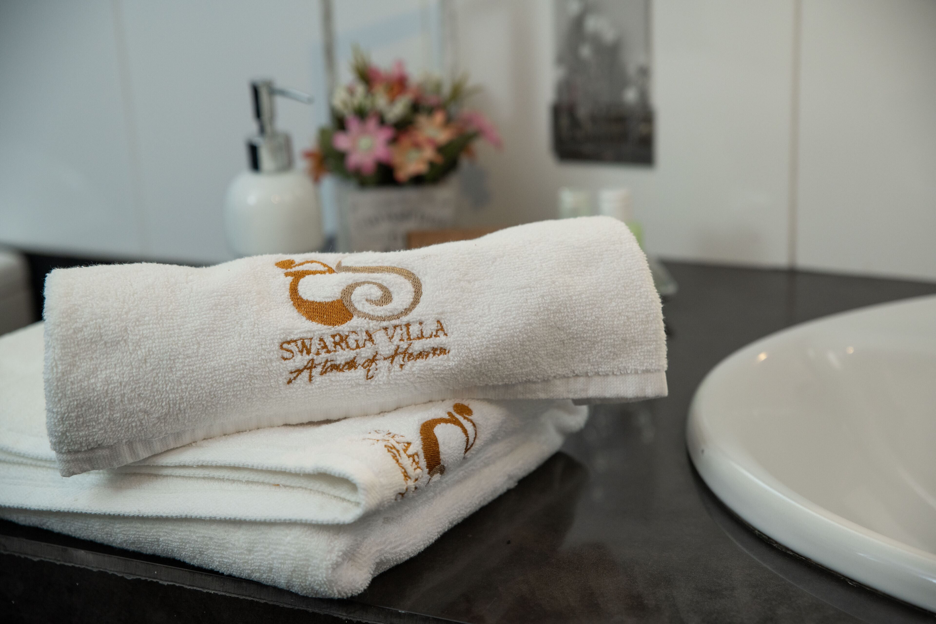 A neatly folded white towel with embroidered text on a bathroom counter.