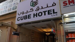 The entrance to the Cube Hotel with a sign in multiple languages, a staircase leading inside, and a storefront with air conditioning units visible. - Cube Hotel Dubai (Dubai)