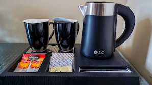 A tray with two black coffee cups, a black electric kettle, and two packets of Nescafe Classic coffee. - Cube Hotel Dubai (Dubai)