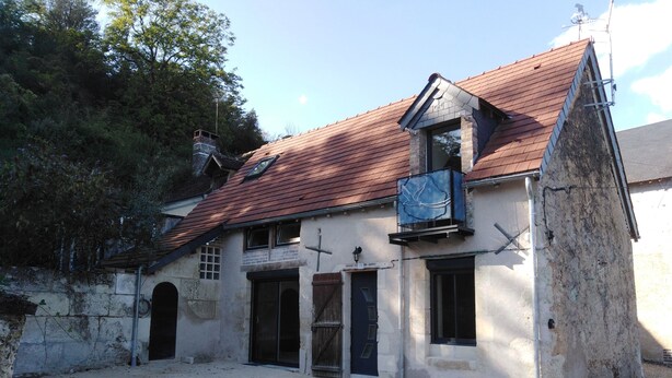 A two-story building with a red-tiled roof, a small balcony, and a cross on the wall. - Gîte mon p'ti bout (LES ROCHES L'EVËQUE)
