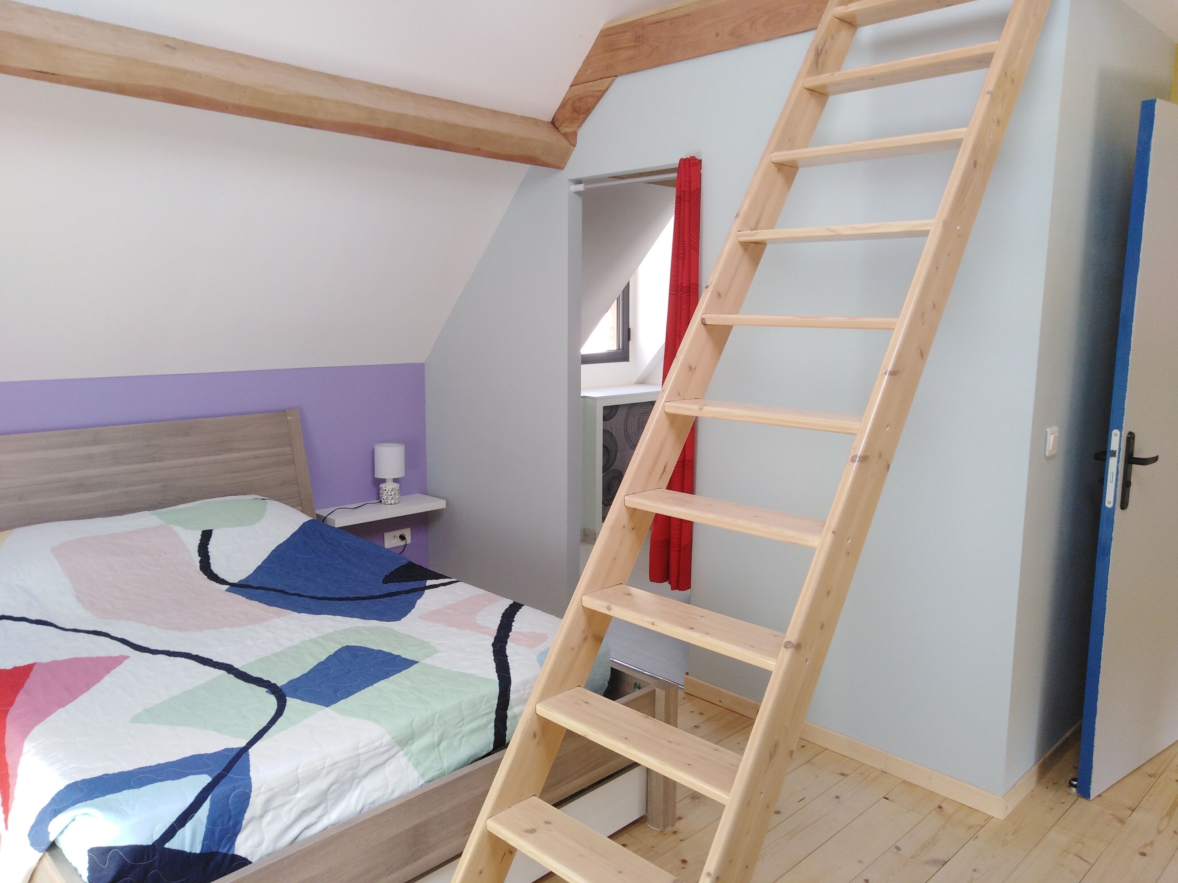 Ein Schlafzimmer mit einem Bett, einer Holzleiter, einem Nachttisch und einem Kleiderschrank.